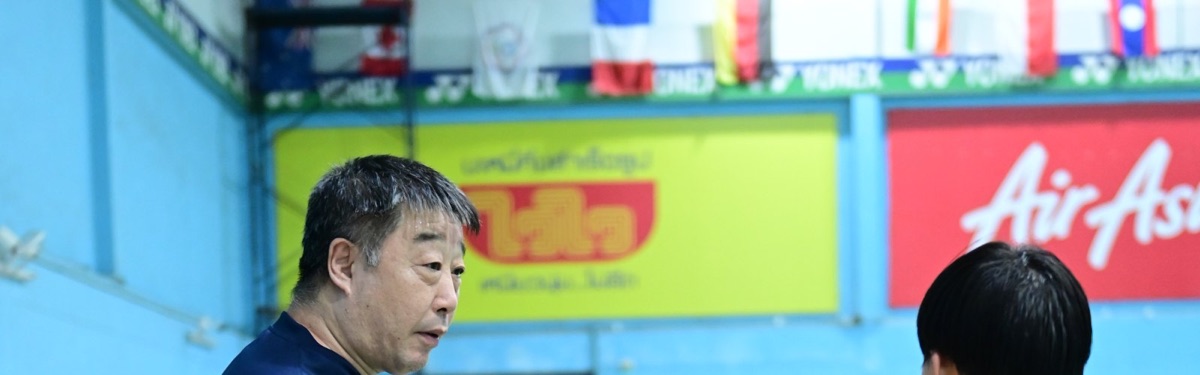 โค้ชคุยกับนักกีฬาในสนามที่ประดับธงนานาชาติ